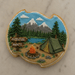 Decorative cookie shaped like a plaque with a camping scene, including a tent, campfire, and mountains from a 4.75 inch Plaque or Frame Metal Cookie Cutter