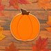 Pumpkin-shaped cookie on a wooden surface with autumn leaves from a 4 inch Pumpkin Metal Cookie Cutter