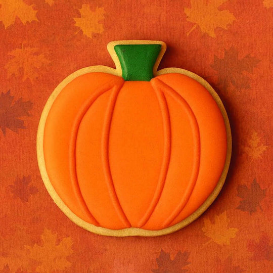 Pumpkin-shaped cookie on an orange background with leaf patterns from a 3.75 inch Pumpkin or Apple Metal Cookie Cutter