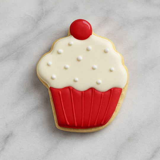 Cookie shaped like a cupcake with red and white icing on a gray surface from a 4 inch Cookie Jar Metal Cookie Cutter