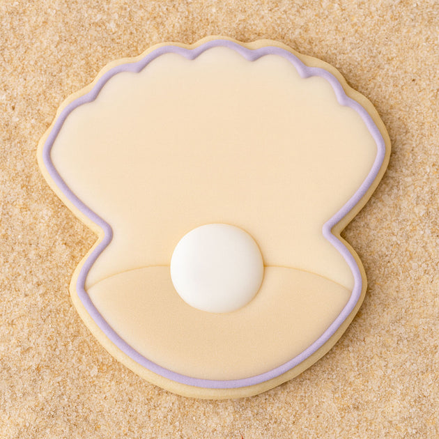 Clam shell with pearl  outlined in purple cookie on a sandy background from a 2 inch Mini Oyster Clam Shell with Pearl Metal Cookie Cutter