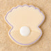 Clam shell with pearl  outlined in purple cookie on a sandy background from a 2 inch Mini Oyster Clam Shell with Pearl Metal Cookie Cutter