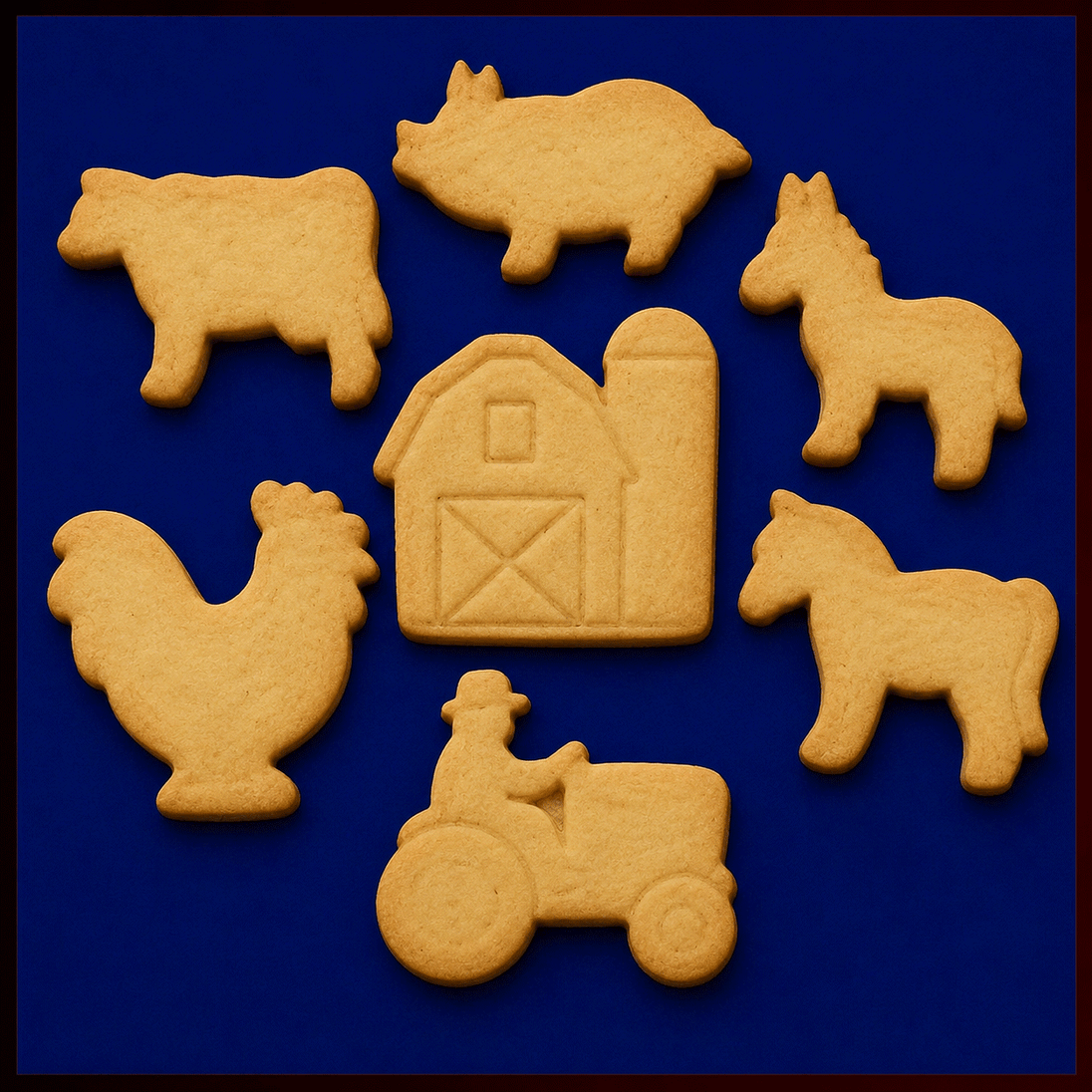 A set of farm-themed sugar cookies arranged on a dark blue background, including a black-and-white cow, pink pig, gray donkey, red barn with silo, green tractor with a farmer figure, brown horse, and white rooster with colorful tail feathers from a Set of Farm Metal Cookie Cutters