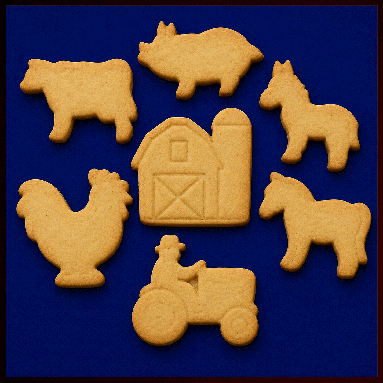 A set of farm-themed sugar cookies arranged on a dark blue background, including a black-and-white cow, pink pig, gray donkey, red barn with silo, green tractor with a farmer figure, brown horse, and white rooster with colorful tail feathers from a Set of Farm Metal Cookie Cutters