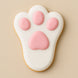 Cookie shaped like a bunny paw with pink pads on a beige background from a 2 inch Mini Bunny Rabbit Foot Metal Cookie Cutter