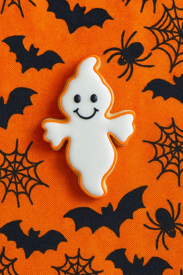 Ghost-shaped cookie on an orange background with Halloween decorations from a 2.5" Mini Ghost Metal Cookie Cutter