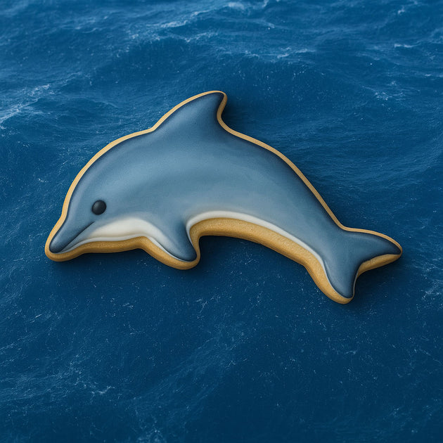 Dolphin-shaped cookie on a blue ocean background from a 2 inch Mini Dolphin Metal Cookie Cutter