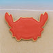 Red crab-shaped cookie on a sandy beach with blue water in the background from a 2.25 inch Mini Crab Metal Cookie Cutter