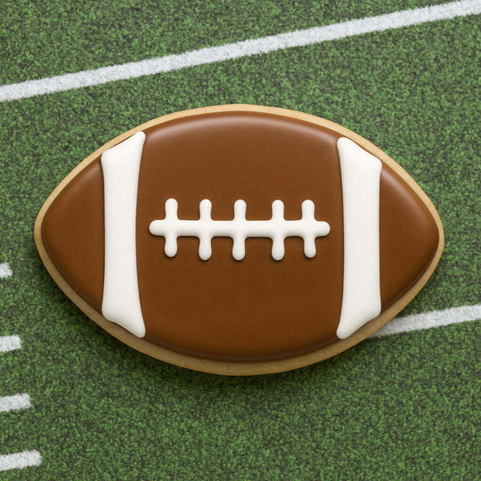Football-shaped cookie on a green field background for 2 inch Mini Football Metal Cookie Cutter