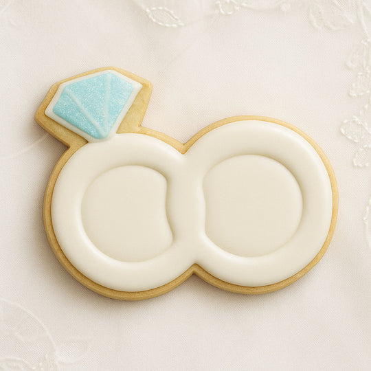 Cookie shaped like a wedding ring with a blue gemstone on a white background from a 1.75 inch Mini Double Wedding Rings Metal Cookie Cutter