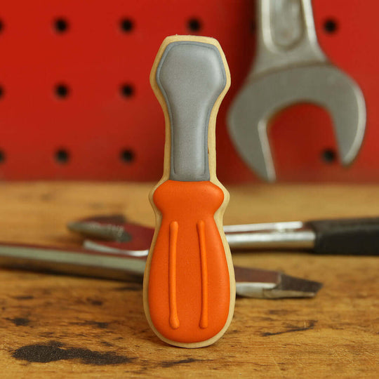 Cookie shaped like a screwdriver with a red tool bench background from a 2 inch Mini Screwdriver Metal Cookie Cutter