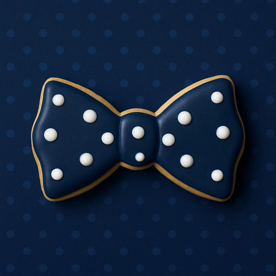 Navy blue bow tie cookie with white dots on a dark blue polka dot background from a 1.75 inch Mini Bow Tie Metal Cookie Cutter