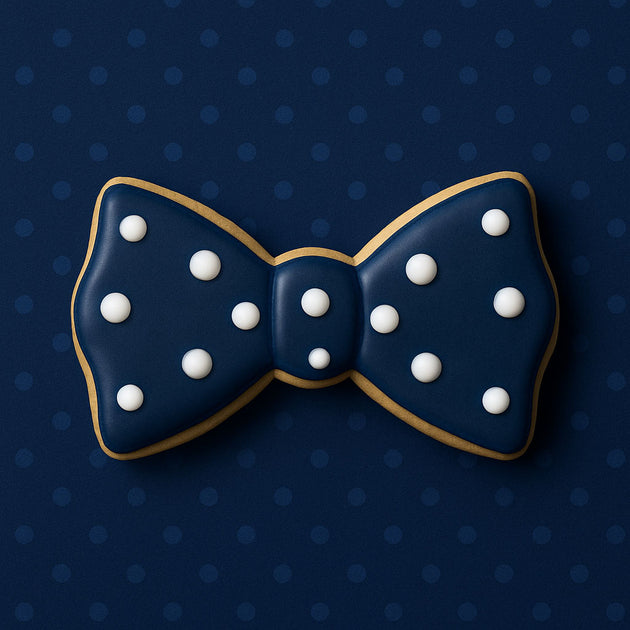 Navy blue bow tie cookie with white dots on a dark blue polka dot background from a 1.75 inch Mini Bow Tie Metal Cookie Cutter