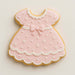 Cookie shaped like a pink dress with white details on a light beige background from a 2 inch Mini Baby Dress Metal Cookie Cutter 
