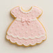 Cookie shaped like a pink dress with white details on a light beige background from a 2 inch Mini Baby Dress Metal Cookie Cutter 