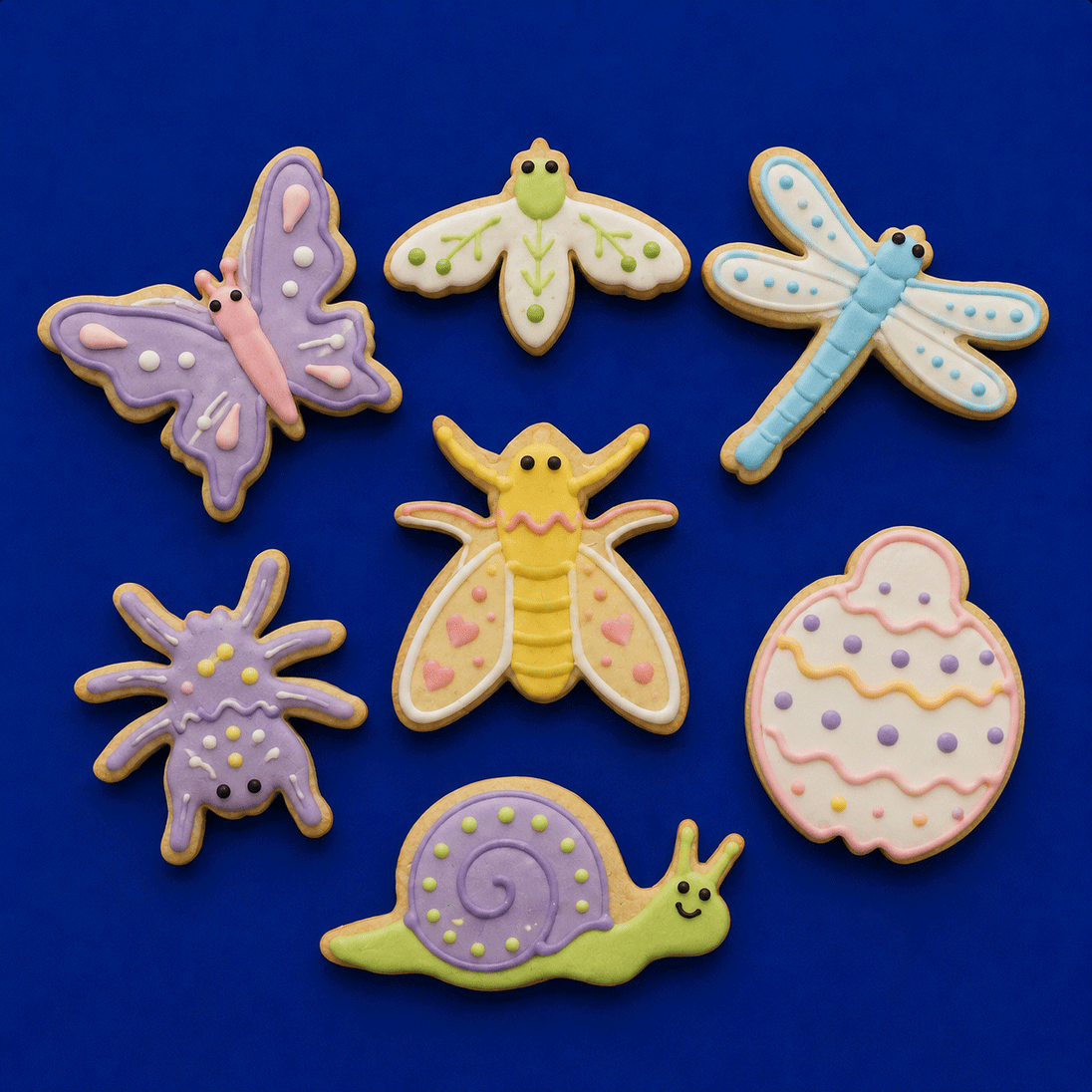 Decorative cookies shaped like insects and a snail on a blue background from a Set of Bugs Metal Cookie Cutters