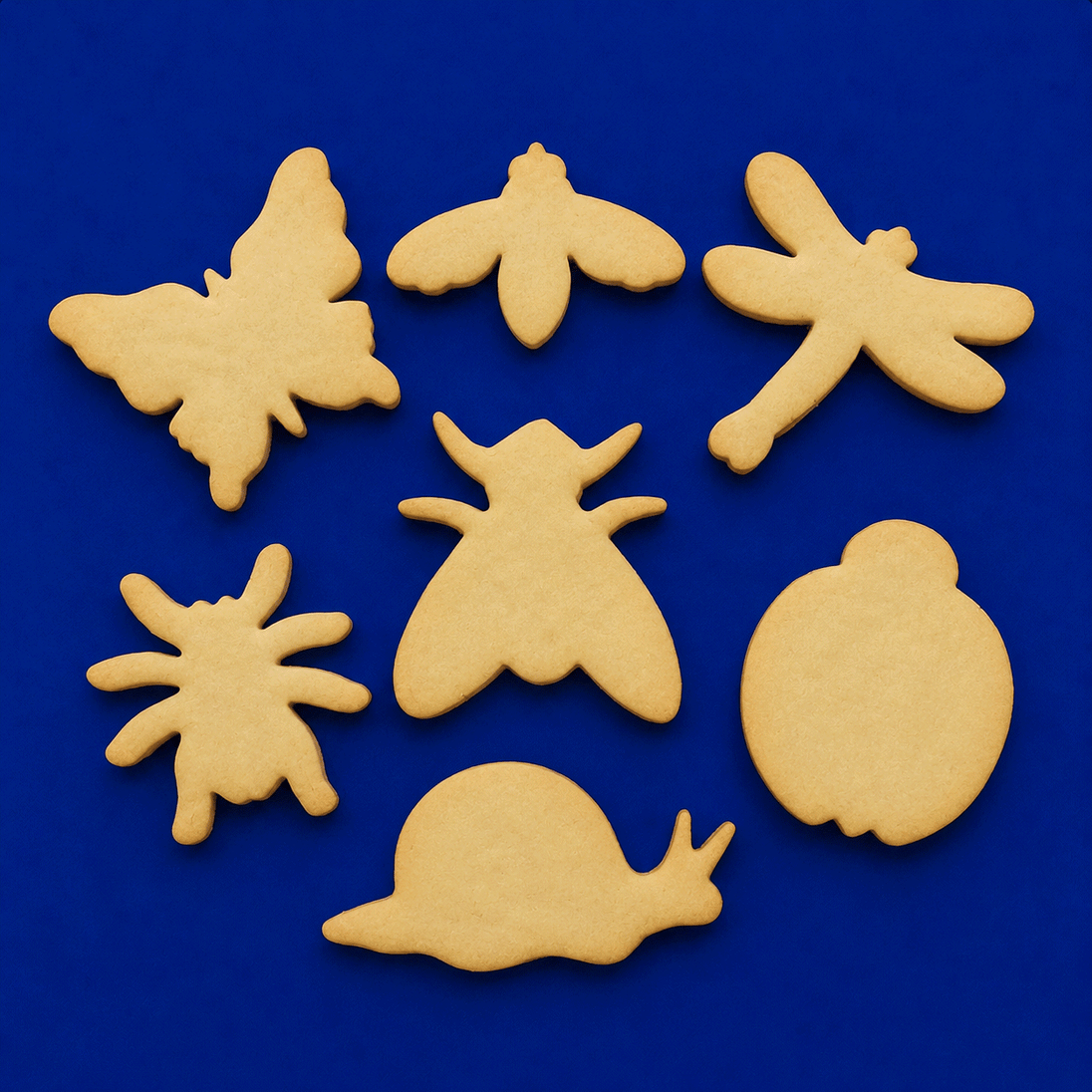 Set of bug-shaped cookies on a blue background from a Set of Bugs Metal Cookie Cutters