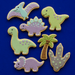 Decorative cookies shaped like dinosaurs and a palm tree on a blue background from a  Set of Dinosaur Metal Cookie Cutters