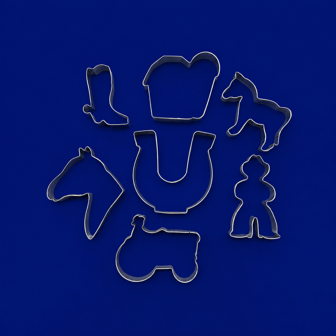 Set of metal cookie cutters with horse and cowboy designs on a blue background from a  Set of Ranch Metal Cookie Cutters