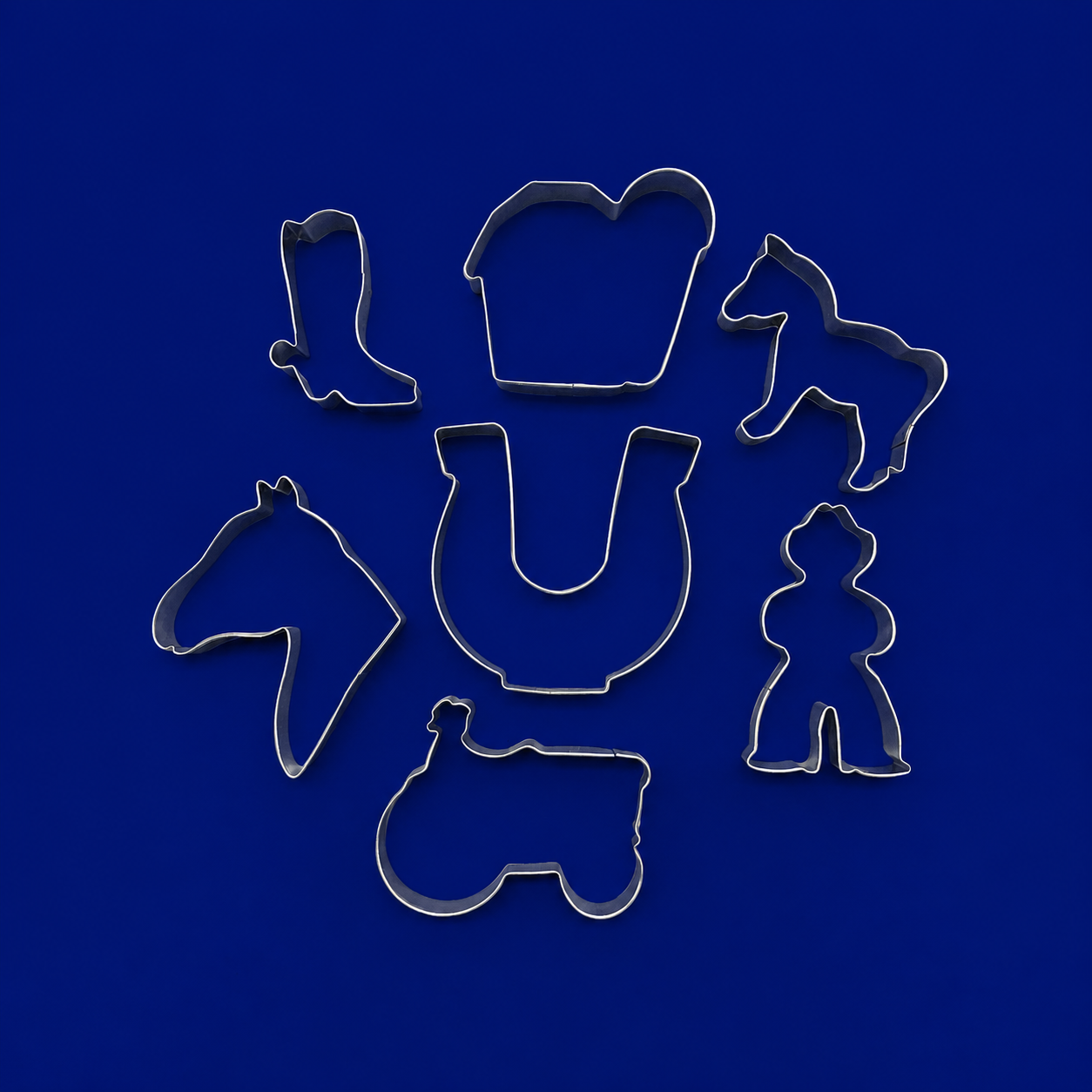Set of metal cookie cutters with horse and cowboy designs on a blue background from a  Set of Ranch Metal Cookie Cutters