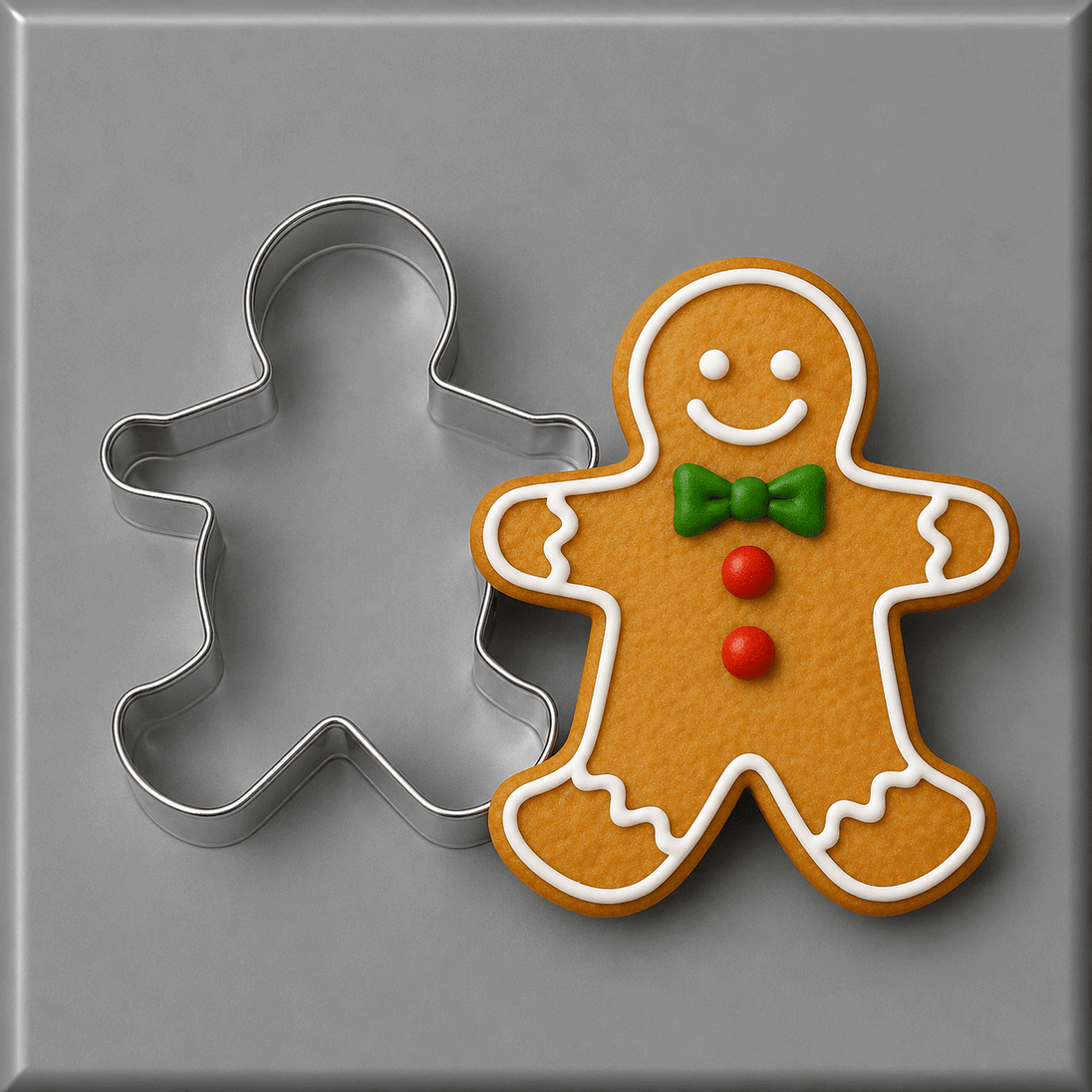 A 5 inch Gingerbread Boy Metal Cookie Cutter shown beside a decorated gingerbread man cookie on a smooth gray surface.