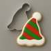 A 3.75 inch Elf Party Ski Hat Metal Cookie Cutter shown next to a decorated sugar cookie shaped like a Santa hat, on a plain gray background.