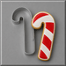 A 5 inch Candy Cane Metal Cookie Cutter shown next to a decorated sugar cookie shaped like a candy cane, on a smooth gray background.