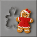 A 3 inch Gingerbread Girl Metal Cookie Cutter shown next to a decorated gingerbread cookie shaped like a girl in a red dress with white icing details, on a gray background.
