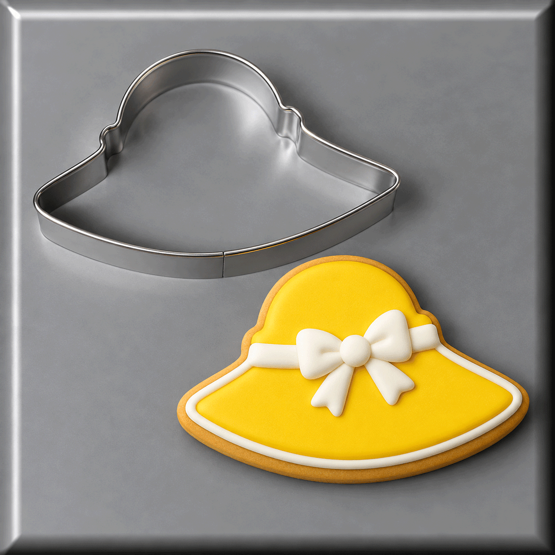 A 4.5 inch Easter Bonnet or Beach Hat Metal Cookie Cutter shown next to a decorated yellow sun hat cookie on a gray background.