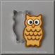 An 3.25 inch Owl Metal Cookie Cutter shown beside an owl-shaped decorated cookie on a gray background. The cookie features brown icing outlines, large white eyes with black pupils, and a small orange beak.