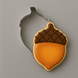 An acorn-shaped cookie with orange and brown icing, shown next to a 2.75 inch Acorn Metal Cookie Cutter on a solid gray background.