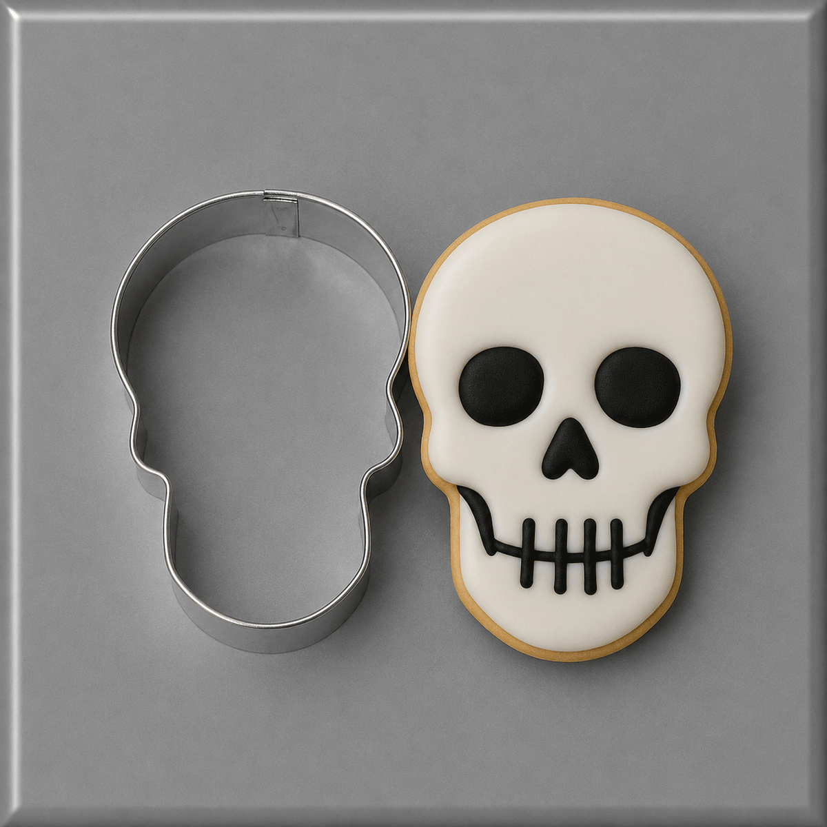 A 3 inch Skull Metal Cookie Cutter shown next to a decorated sugar skull cookie with white icing, black details, and a golden-brown edge, on a gray background.