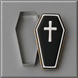 A coffin-shaped cookie with black icing, a white cross, and white border trim, shown next to a 4 inch Coffin Metal Cookie Cutter on a gray background.