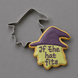 A 4 inch Witch Head Metal Cookie Cutter is shown beside a decorated sugar cookie in the shape of a witch hat with the phrase 'If the hat fits' in purple icing, on a smooth gray background.