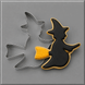 A Halloween-themed cookie cutter set on a gray background, featuring a witch silhouette cutter with a black and yellow decorated cookie inside, and a 3.75 inch Flying Witch Metal Cookie Cutter behind it.