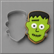 A Frankenstein-themed sugar cookie next to a 3.25 inch Frankenstein Monster Metal Cookie Cutter, set against a neutral gray background.