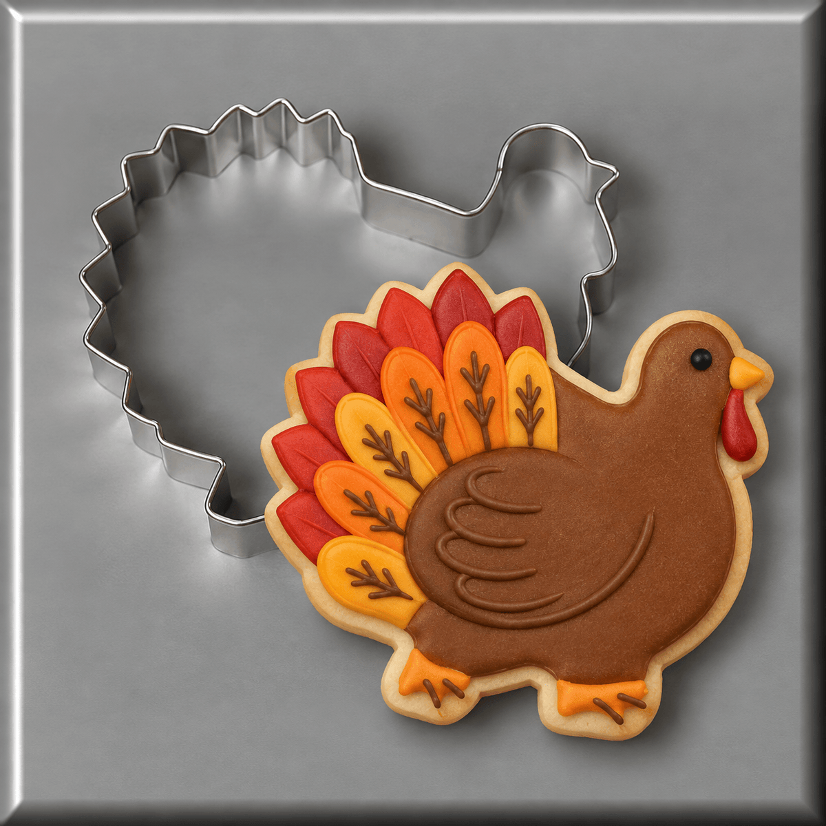 A 4 inch Turkey Metal Cookie Cutter is shown behind a decorated turkey-shaped sugar cookie on a gray background.