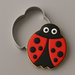 A decorated ladybug-shaped cookie with red and black icing, white eyes, and black spots, shown next to a 3 inch Ladybug Metal Cookie Cutter on a neutral gray background.