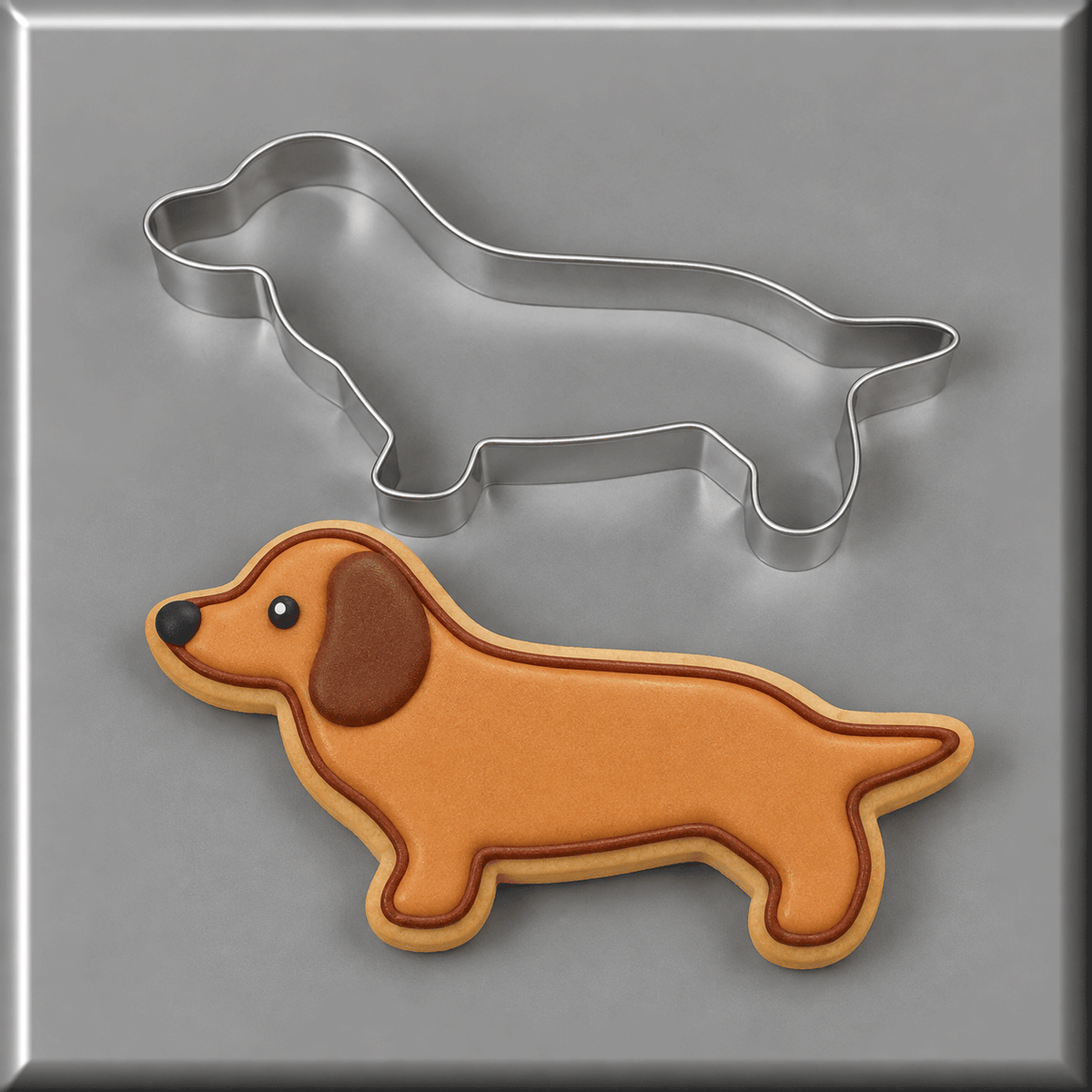 A 5 inch Primitive Dachshund Metal Cookie Cutter above a decorated dachshund-shaped sugar cookie on a gray background.