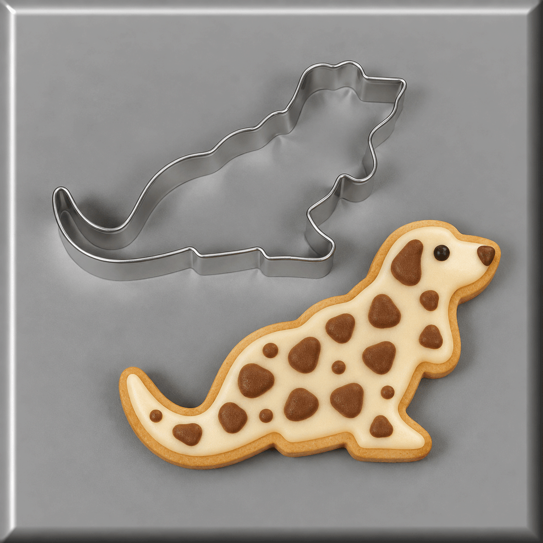 A 5 inch Basset Hound Metal Cookie Cutter shown above a decorated dog-shaped sugar cookie with cream icing and brown spots, on a gray background.