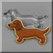 A dachshund-shaped brown cookie with gold icing outlines and a 5.5 inch Dachshund Metal Cookie Cutter behind it, set against a gray background.