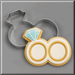 A 4.5 inch Double Engagement Wedding Rings Metal Cookie Cutter is shown behind a decorated sugar cookie shaped like two interlocking rings with a light blue diamond on top, set on a gray background.