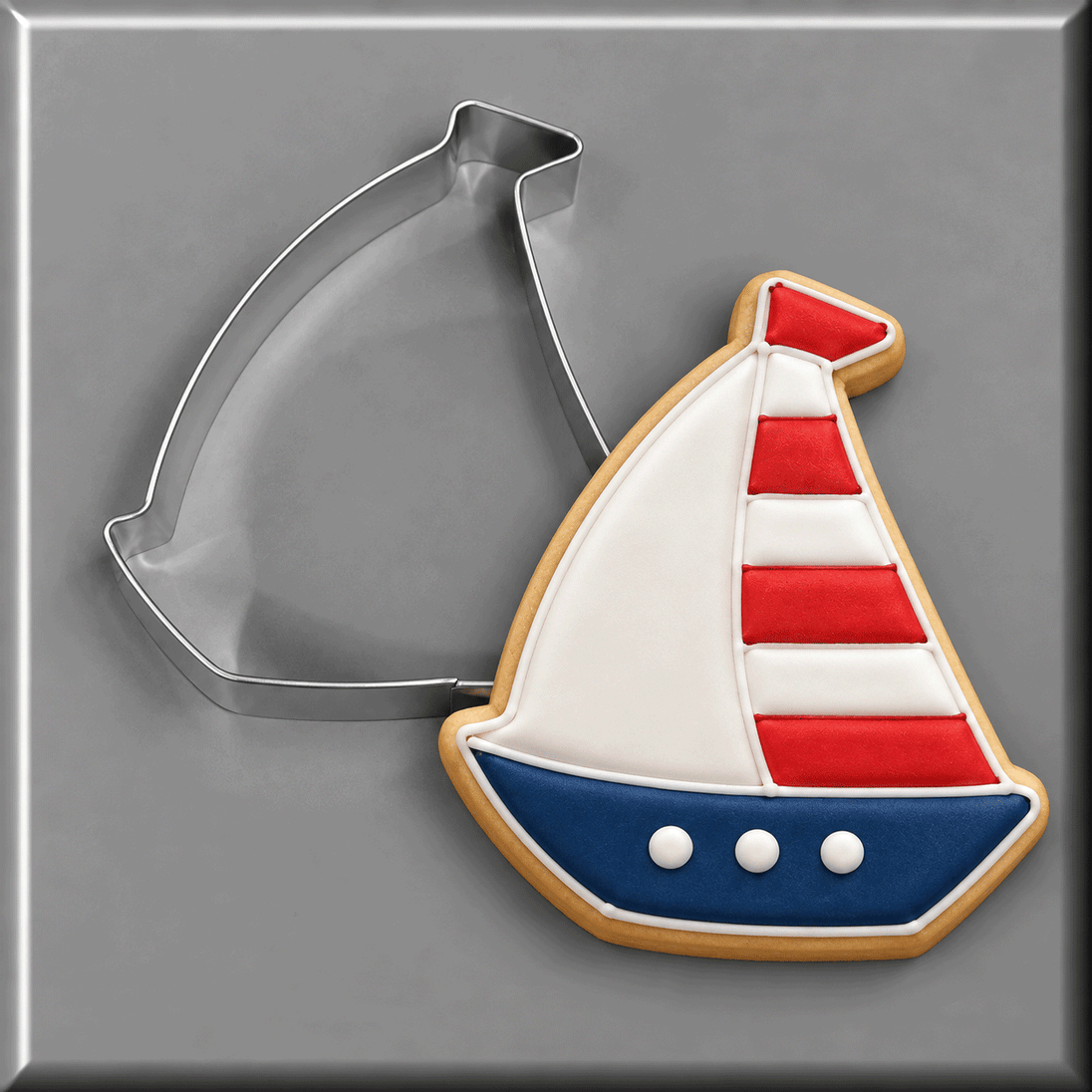 Sailboat cookie next to a 4 inch Sailboat Metal Cookie Cutter