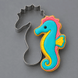 A 4 inch Seahorse Metal Cookie Cutter shown beside a decorated seahorse-shaped sugar cookie on a smooth gray background.