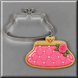 A pink and gold purse cookie next to a 4 inch Purse Metal Cookie Cutter