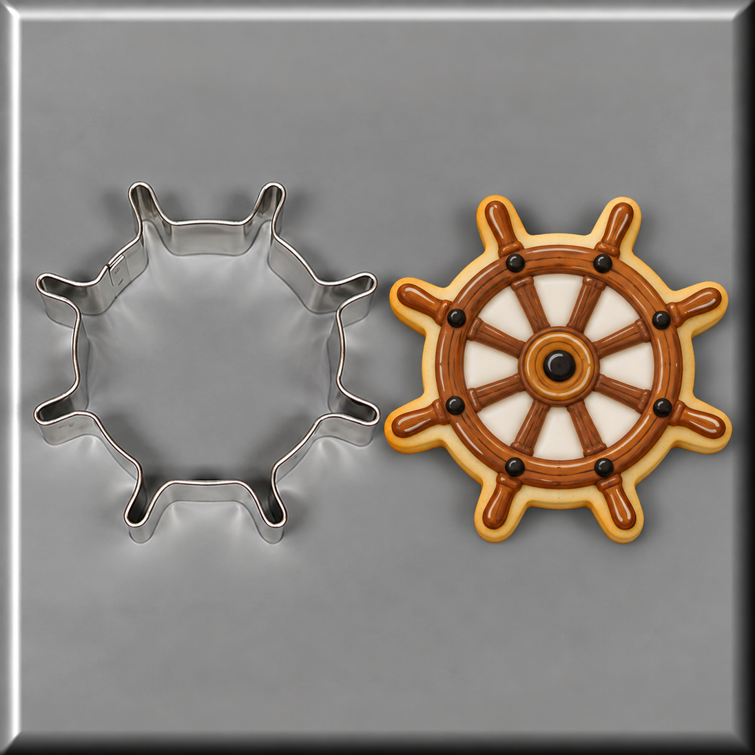 A ship's wheel shaped sugar cookie with brown icing and white sections, shown next to a 4 inch Ship's Wheel Metal Cookie Cutter on a gray background.