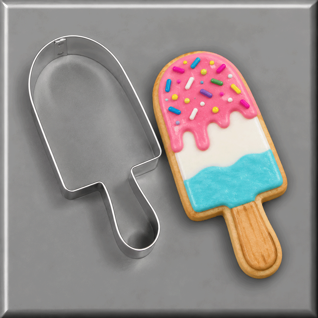 A Popsicle shaped cookie next to a 4.5 inch Popsicle Metal Cookie Cutter