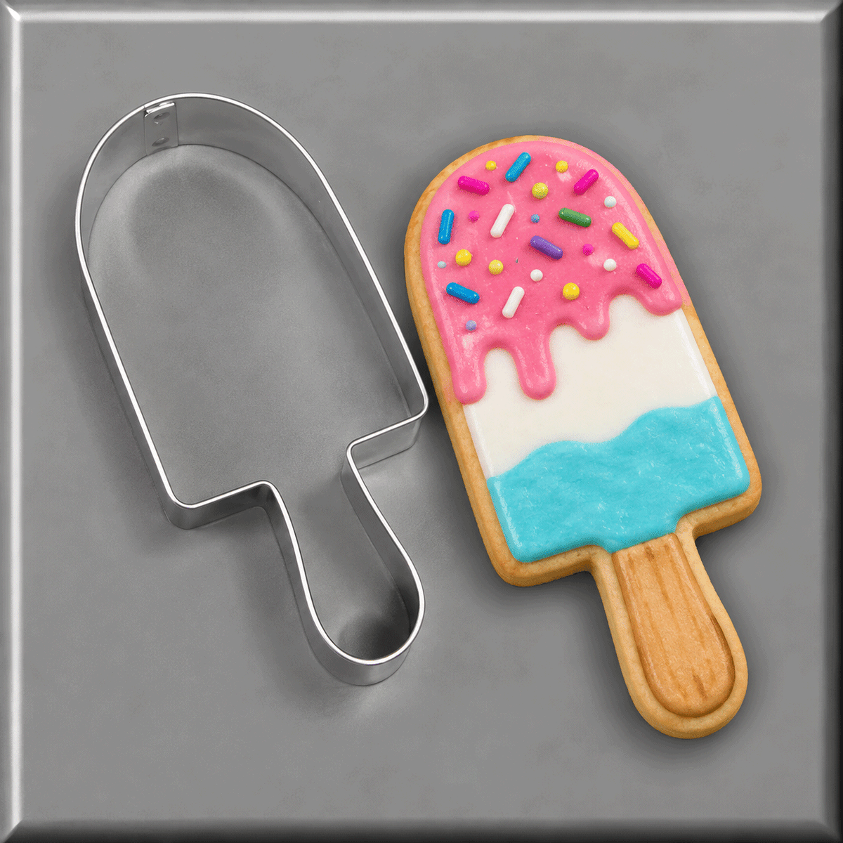 A Popsicle shaped cookie next to a 4.5 inch Popsicle Metal Cookie Cutter