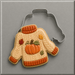 decorated cookie to look like a fall sweater with pumpkin on it along with the cutter from a 4.25 inch Ugly Sweater Metal Cookie Cutter