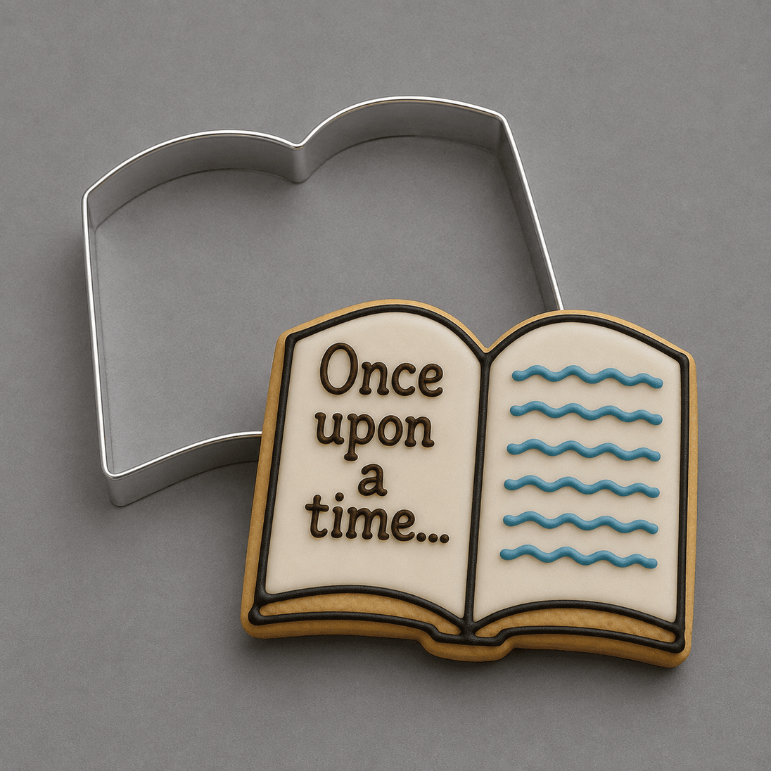 An open book-shaped cookie with white icing, brown lettering reading 'Once upon a time next to a 4.25 inch Open Book Metal Cookie Cutter
